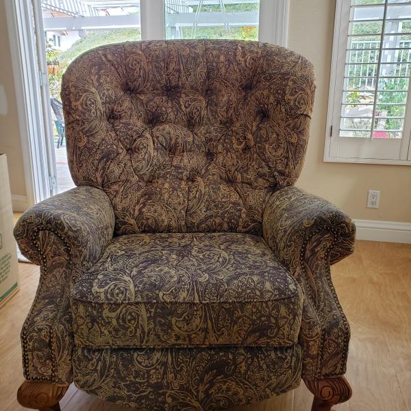 Photo of Large tan & black tufted reclining chair with wooden claw feet.