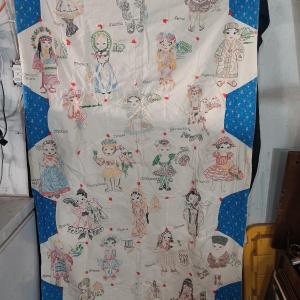 Photo of Antique Child's quilt hand stitched with people from different countries all ove