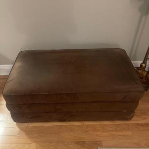 Photo of Lazy Boy brown suede storage ottoman. Has rollers for easy movement. 43” wide,