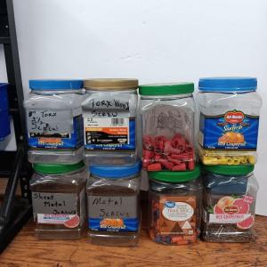 Photo of 8 lidded plastic containers with assortment of different sized wire nuts - nails