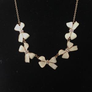 Photo of Gold toned necklace creme colored bows necklace