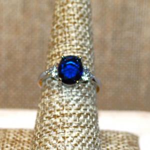 Photo of Size 8 Deep Blue Oval Center Stone Ring with 3 Clear Stones Side Accents on a Si