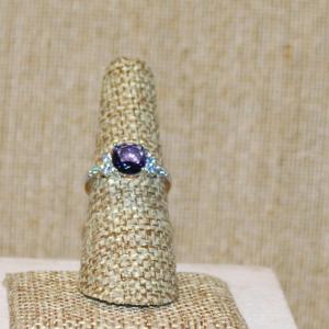 Photo of Size 7 Round Purple Stone Ring with Clear Stone Side Accents on a Gold Tone SPLI